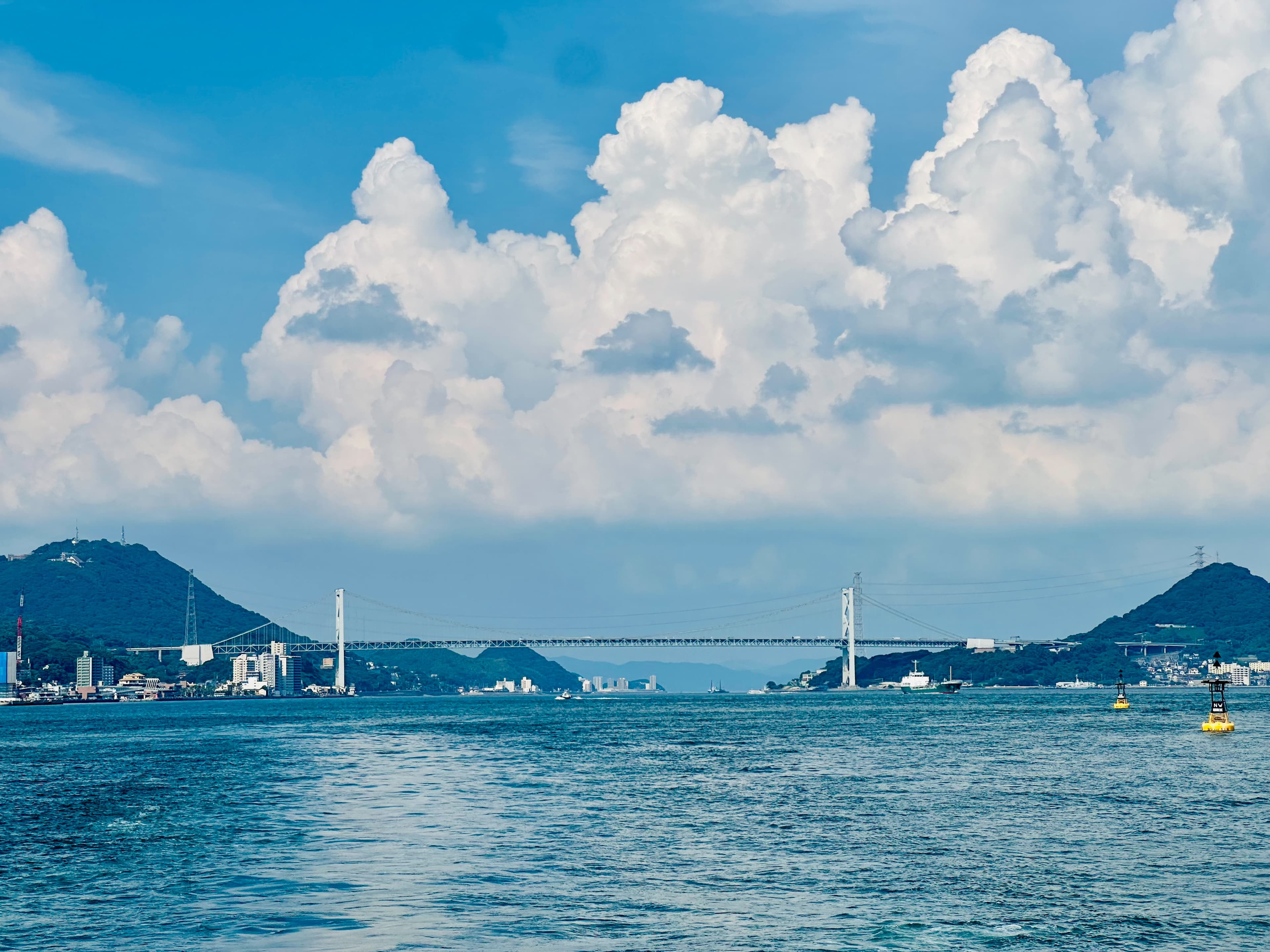 A bridge across the strait beneath summer clouds